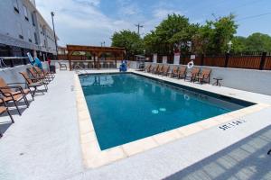 a swimming pool with chairs and a table and a building at Hampton Inn & Suites Denton in Denton