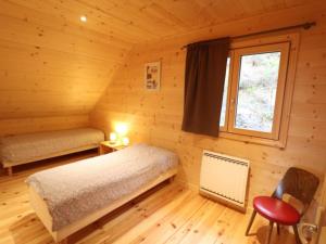 ein Schlafzimmer in einem Blockhaus mit einem Bett und einem Fenster in der Unterkunft Gîte Saint-Jacques-des-Blats, 4 pièces, 8 personnes - FR-1-742-259 in Saint-Jacques-des-Blats