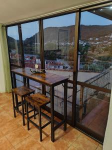 mesa y sillas en una habitación con ventana grande en Casinha da Ladeira 3360, en Penacova
