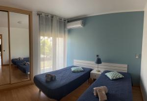 a blue room with two beds and a window at Beach House Carmen 2 in Monte Gordo