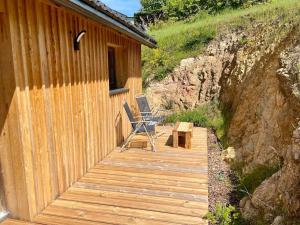 eine Holzterrasse mit 2 Stühlen und einem Tisch in der Unterkunft Le Chalet in La Meilleraie-Tillay