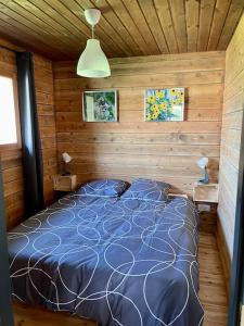 een slaapkamer met een bed in een houten hut bij Le Chalet in La Meilleraie-Tillay