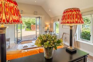 a living room with two lamps and a vase of flowers on a table at Elegant luxurious cottage - The Dove House in Ipswich