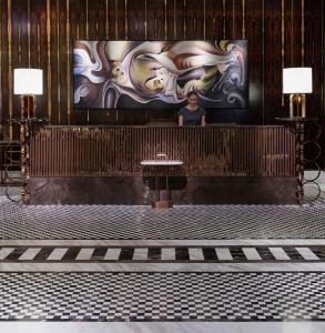 a woman standing in front of a large painting on a wall at Waldorf Astoria Dubai International Financial Centre in Dubai