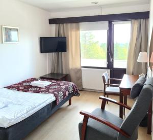 ein Hotelzimmer mit einem Bett, einem Stuhl und einem Schreibtisch in der Unterkunft Hotel Julie in Joensuu