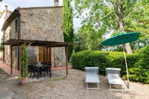 eine Terrasse mit 2 Stühlen, einem Tisch und einem Sonnenschirm in der Unterkunft GHIZZOLO Residence - Refurbished 2024 in Montaione