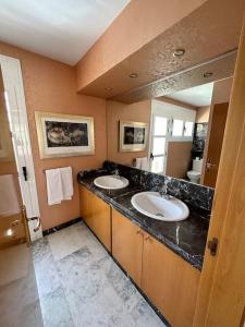 a bathroom with two sinks and a large mirror at Antídoto House Montesión in Toledo