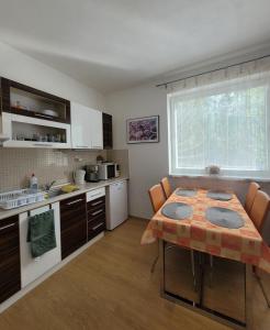 a kitchen with a table with chairs and a kitchen with a tableablish at Apartmán IRIS Podhájska in Podhájska