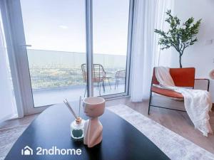 a living room with a table in front of a large window at Homey 1 Bedroom with Relaxing Zabeel Park View in Dubai