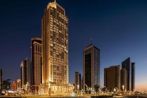 a city skyline with tall skyscrapers at night at Wyndham Grand Doha West Bay Beach in Doha