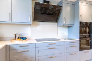 a kitchen with white cabinets and a stove top oven at Owls Nest Barn in Harescombe