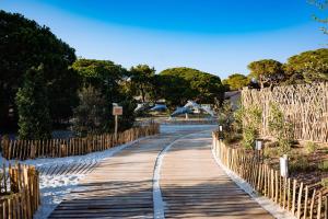 un chemin en bois dans un parc avec une clôture dans l'établissement Le Hameau Des Pesquiers Ecolodge & Spa, Curio Collection By Hilton, à Hyères