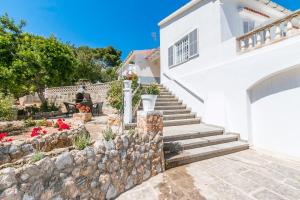 a white house with stairs and a stone wall at Villa los brezos in Playa de Palma