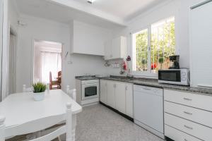 a white kitchen with white cabinets and a white table at Villa los brezos in Playa de Palma