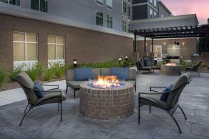 eine Terrasse mit einer Feuerstelle und Stühlen sowie ein Gebäude in der Unterkunft Homewood Suites By Hilton Greenville, NC in Greenville