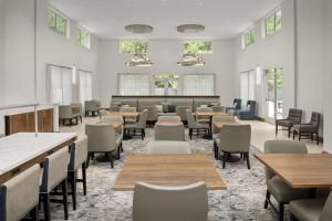Homewood Suites By Hilton Greenville, NC في غرينفيل: غرفة انتظار مع طاولات وكراسي ونوافذ
