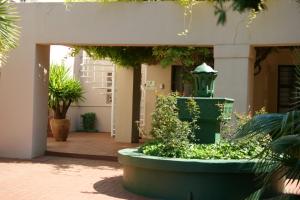 une cour avec une fontaine verte et des plantes dans l'établissement Lakeside Guesthouse, à Lichtenburg