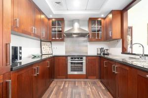 - une cuisine avec des placards en bois, un évier et une cuisinière dans l'établissement Ahlan Holiday Homes Elegant 29 Blvd Home, à Dubaï