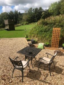 una mesa de picnic y 2 sillas sentadas en un patio de grava en No 1 Hut Lane, a cosy Hut, heating, hot water and a magnificent view for 2, en Dorchester