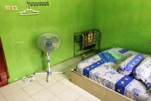 ein Schlafzimmer mit einem Ventilator und einer grünen Wand in der Unterkunft SPOT ON 93014 Griya Nautika Sukodono in Sidoarjo