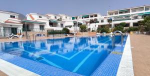 a large blue swimming pool with buildings in the background at Bungalow Palo Blanco Ocean View 250 m to the beach in Adeje