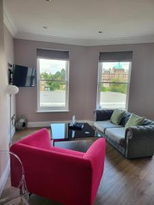 a living room with a couch and two windows at Harrogate Lifestyle Luxury Serviced ApartHotel in Harrogate