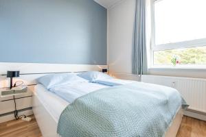 een bed in een kamer met een raam en een sprei bij Steger-Hüs Wohnung 20 in Rantum