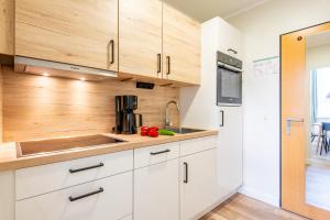 a kitchen with white cabinets and a sink at Steger-Hüs Wohnung 16 in Rantum +13 photos