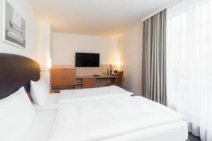 a hotel room with a bed and a television at IntercityHotel Wien in Vienna