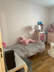 um urso de peluche cor-de-rosa deitado em cima de uma cama em Appartement proche de paris avec jardin em Meudon