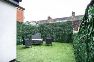a patio with chairs and a table and a green hedge at Cosy Cruise Cribs Ltd in Stoke on Trent