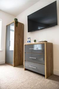 a room with a dresser with a flat screen tv on the wall at Cosy Cruise Cribs Ltd in Stoke on Trent