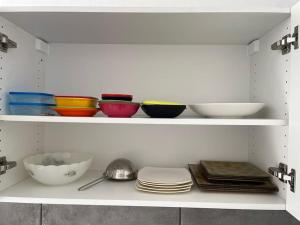 a white shelf with bowls and plates on it at Le Brumby - Internet Netflix draps serviettes café in Joigny