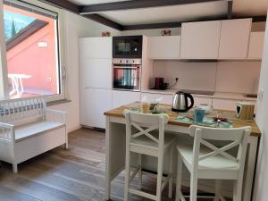 cocina con armarios blancos, mesa y sillas en Aros Mountain Lake Iseo Hospitaliy, en Pisogne