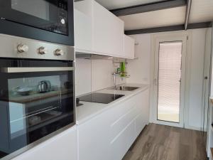 una cocina con armarios blancos y fregadero en Aros Mountain Lake Iseo Hospitaliy, en Pisogne