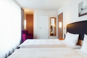 a hotel room with two beds and a window at IntercityHotel Wien in Vienna