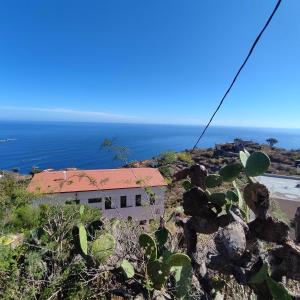 una casa en una colina con el océano en el fondo en Hostal Albergue Garafía El Tablado, en Tablado de la Montañeta