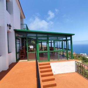 Tablado de la Montañeta的住宿－Hostal Albergue Garafía El Tablado，一座有绿色屋顶的建筑,以海洋为背景