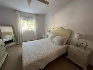 a white bedroom with a bed and a mirror at Marian’s House in Fuengirola
