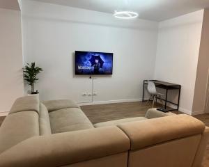 sala de estar con sofá y TV en la pared en Scandinavian Apartments AL en Tirana