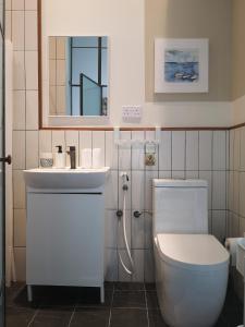 ein Badezimmer mit einem WC, einem Waschbecken und einem Spiegel in der Unterkunft Little Garden private pool villa in Al Ḩamrāʼ