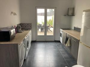 a kitchen with white appliances and a door to a patio at Maison tout confort in Corbie
