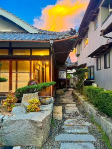 una casa con una pasarela de piedra junto a un edificio en Guesthouse Omoya en Matsuyama