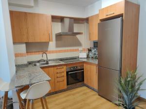 a kitchen with wooden cabinets and a stainless steel refrigerator at Acogedor apartamento en Boiro in Boiro