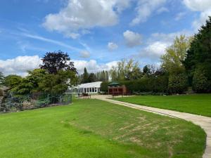 a grassy yard with a white building at ABRIDGE PANORAMIC House in Theydon Bois