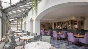un restaurante con mesas y sillas de color púrpura y un bar en The Glenview Hotel & Leisure Club, en Newtown Mount Kennedy