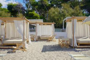 a group of chairs and umbrellas on a beach at Praia Art Resort - Small Luxury Hotels of the world in Le Castella