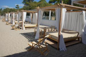 a row of beds and chairs on the beach at Praia Art Resort - Small Luxury Hotels of the world in Le Castella
