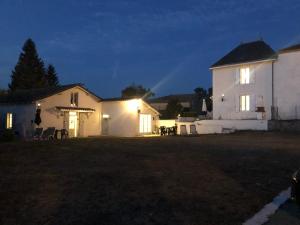 uma casa branca com luzes acesas num quintal à noite em Gîte des Tournesols em Oradour-Fanais