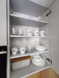 a cupboard filled with white cups and saucers at Matteo Aparts in Szklarska Poręba